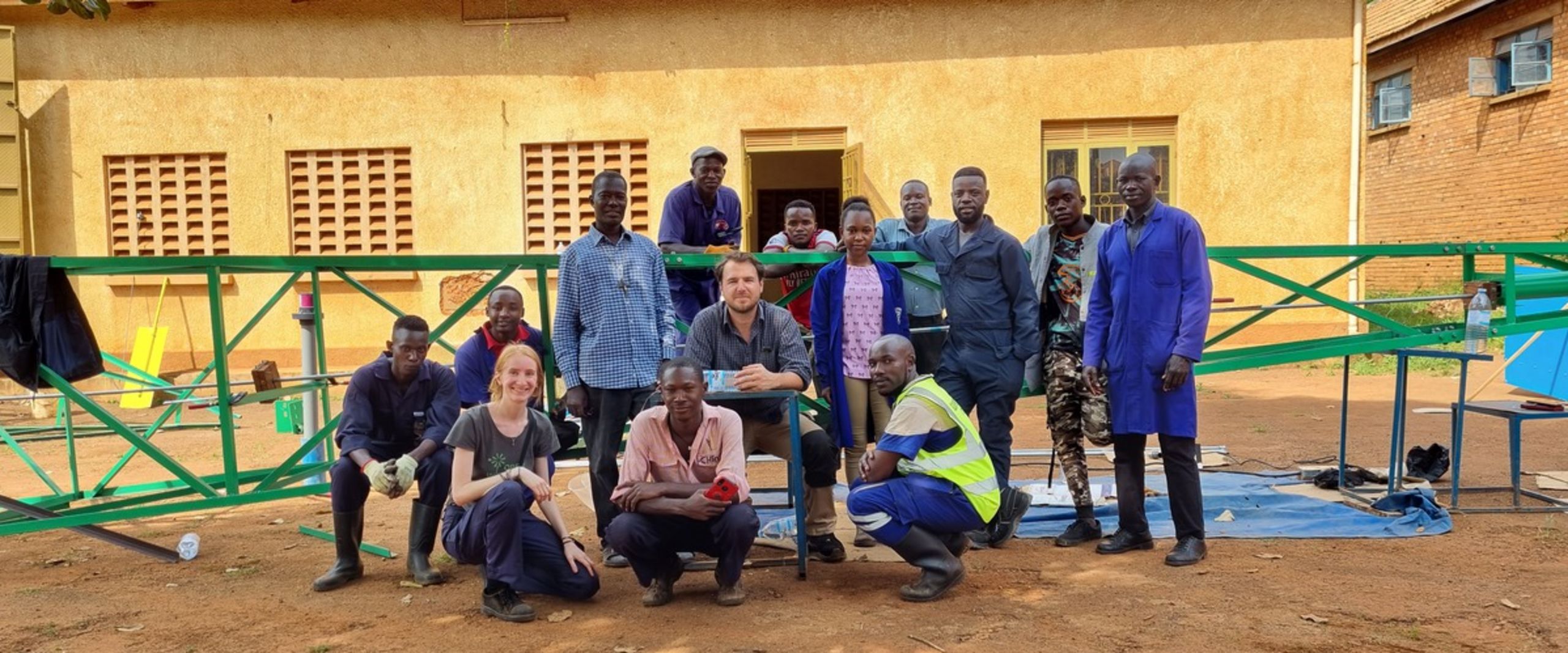 Gruppenbild mit M&auml;nnern und frauen vor einer H&uuml;tte.