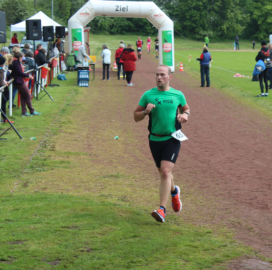 Ein L&auml;ufer auf einem Feldweg und im Hintergrund stehen mehrere Personen.