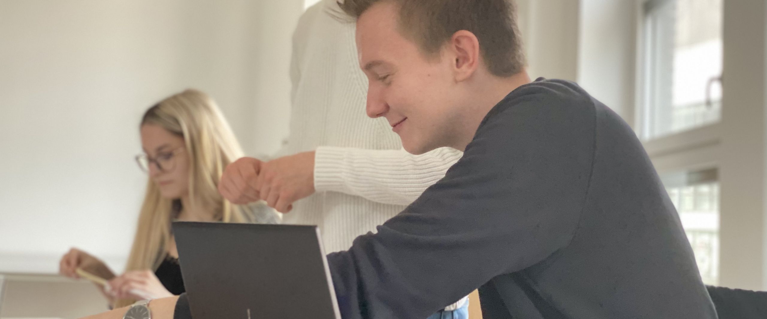 Freiraum Zwei junge Männer und eine Frau arbeiten an Tischen.