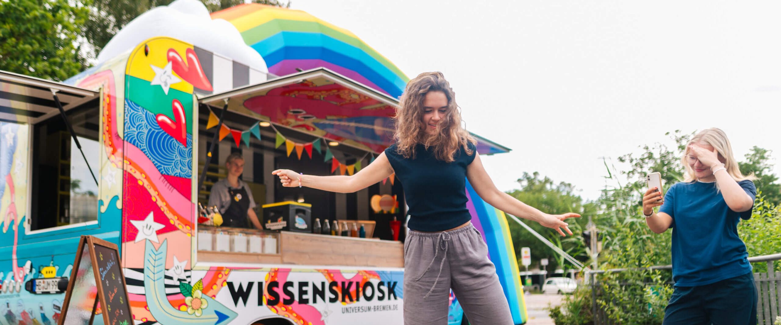 Universum Wissenskiosk Bunter Kiosk. Davor sind zwei Menschen aktiv