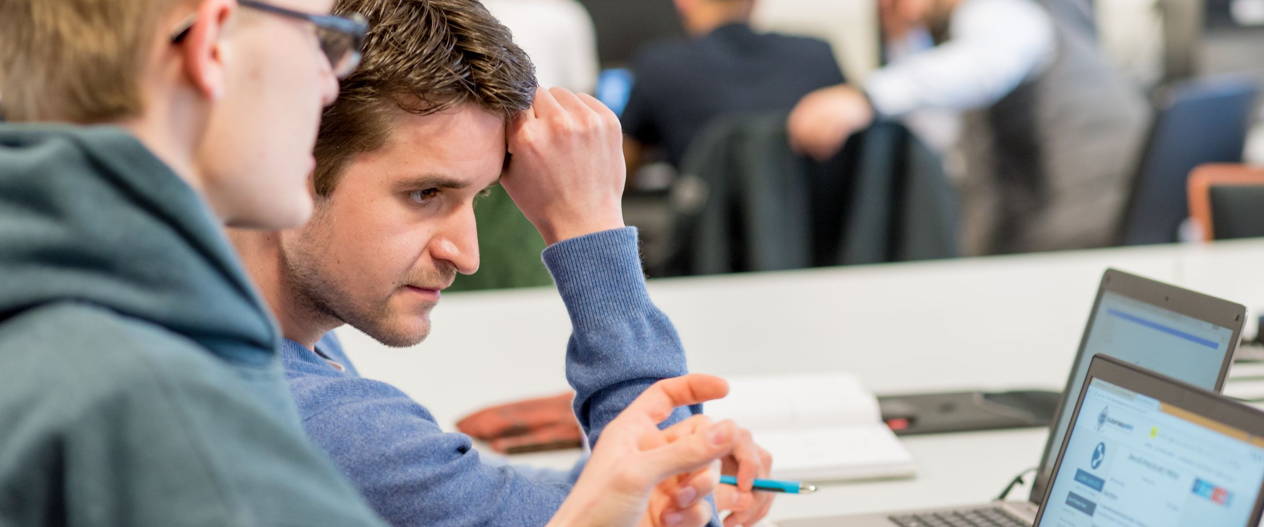 Zwei Studenten sehen sich etwas an einem Laptop an.