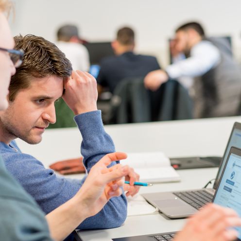 Zwei Studenten sehen sich etwas an einem Laptop an.