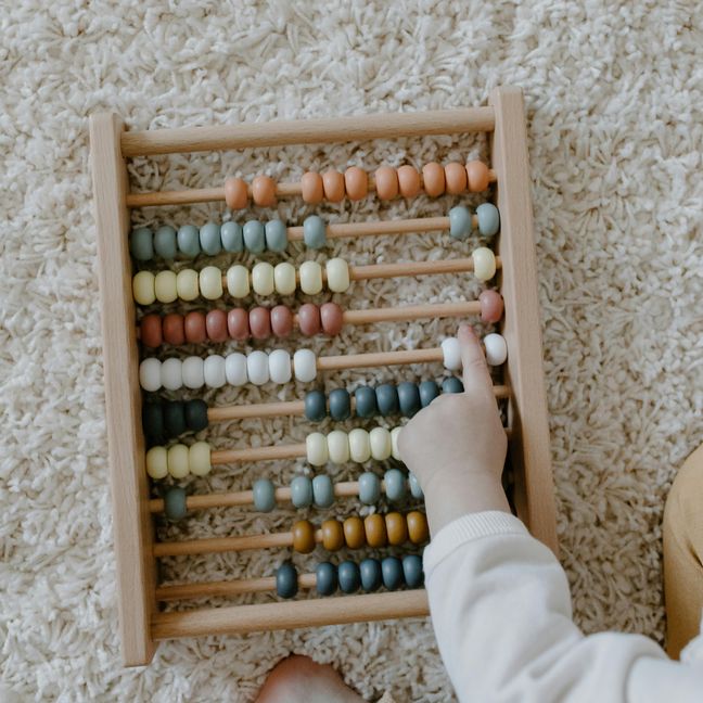 Finger von einem Kleinkind zeigt auf einen Abakus