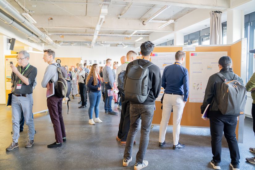 Besucher:innen der 3. Konferenz der Norddeutschen Wärmeforschung sehen sich die Posterpräsentation an. 
