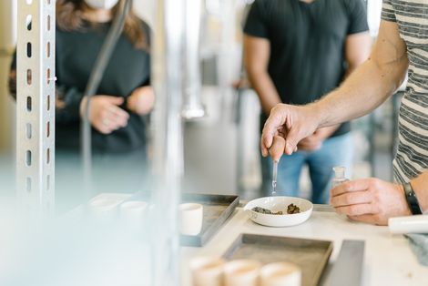 Ein Student macht ein Experiment und dahinter schauen zwei Studierende zu.