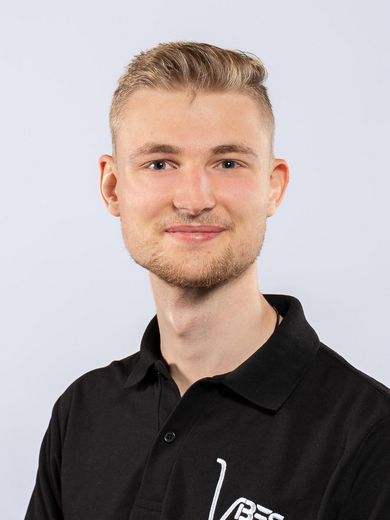 Auf dem Bild ist Hannes Suttrop zusehen. Er hat kurzes blondes Haar und tr&auml;gt ein schwarzes Polo-Shirt.