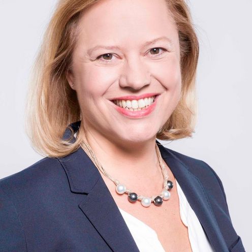 Portrait einer Frau mit wei&szlig;er Bluse und Jacket mit blonden schulterlangen Haaren.