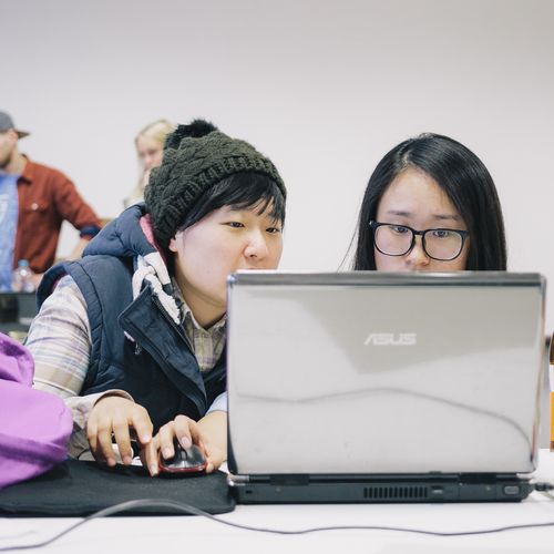 Zwei Studierende sitzen vor einem Laptop