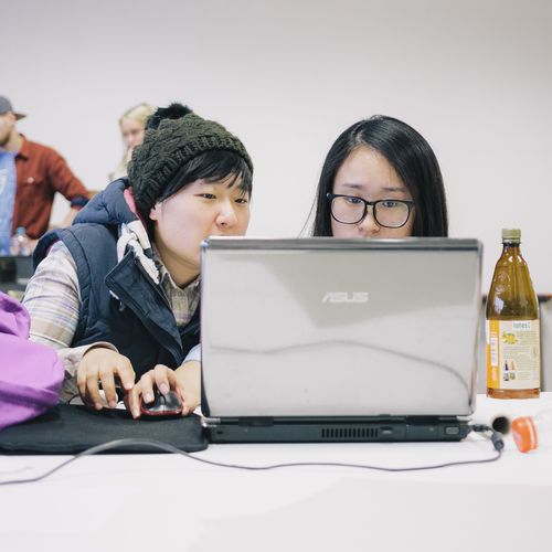 Zwei Studierende sitzen vor einem Laptop