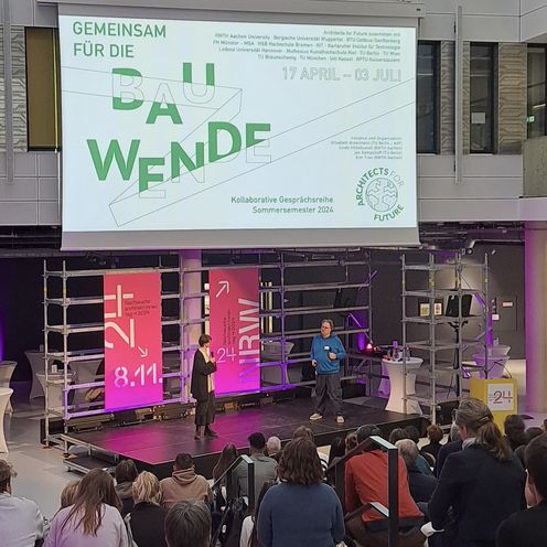 B&uuml;hne mit gro&szlig;em Banner vor Publikum