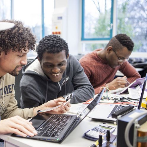 Studierende sehen schauen gemeinsam auf den Bildschirm eines Laptops.