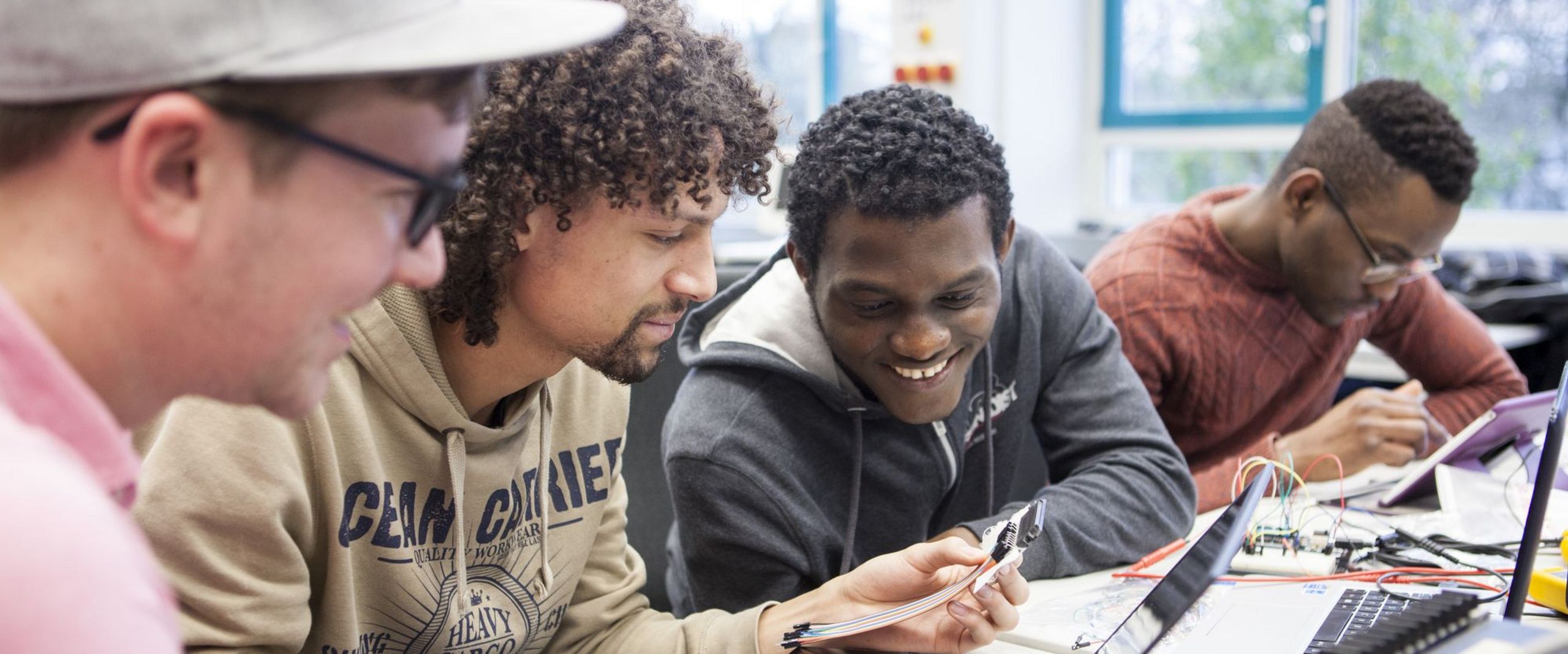 Studierende sehen schauen gemeinsam auf den Bildschirm eines Laptops.