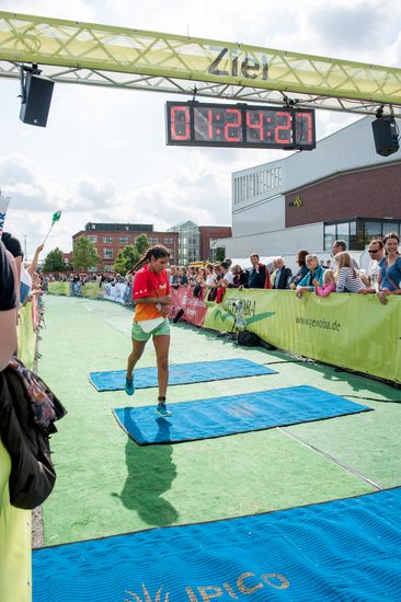 Eine L&auml;uferin sprintet durch das Ziel. Im Hintergrund sind mehrere Zuschauer.