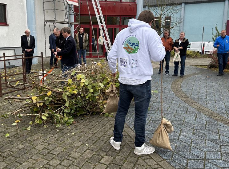Praktiker-Tag für Sachsen-Anhalt in Staßfurt am 08.11.2025, Foto-9, Motiv: Projektleiter Prof. Thomas Klefoth mit Jutesäcken vor Totholz-Bündel