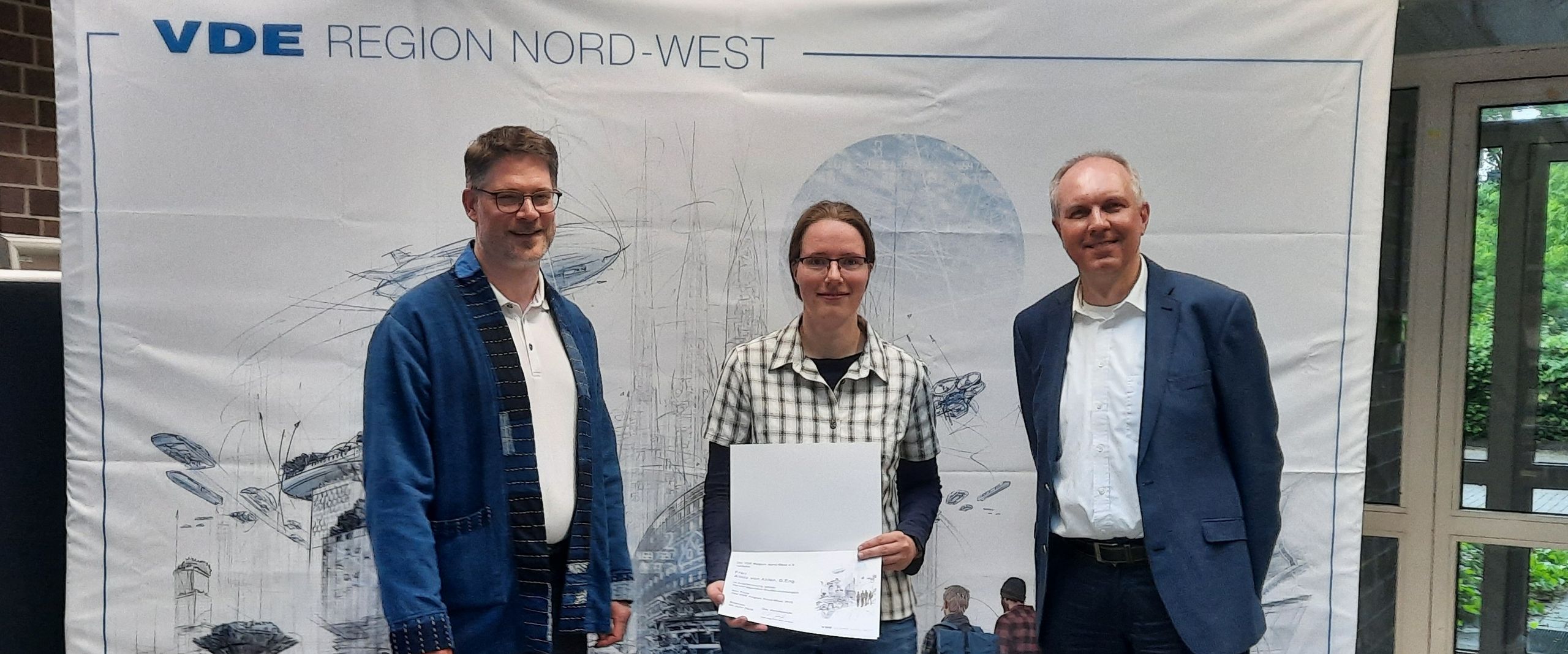 gruppenbild mit einer Frau und zwei M&uuml;nnern. Die frau h&auml;lt eine Urlunde in die Kamera
