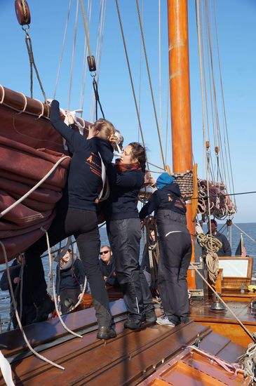 Menschen auf einem Hozboot. Sie holen die Segel ein.