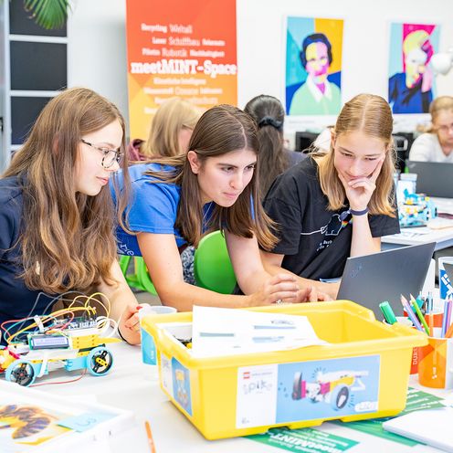 meetMINT-Space Sommer-Workshop 2025 Mehrere Schülerinnen im meetMINT-Lab programmieren und bauen mobile Roboter.