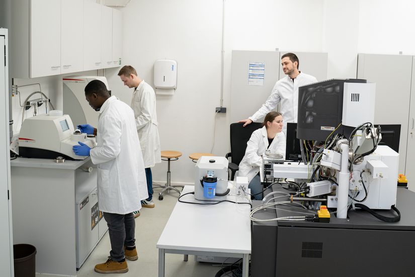 M&auml;nne rund eine Frau stehen im Kittel im labor und arbeiten