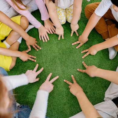 Kinder in einer Kita sitzen im Kreis und zeigen ihre H&auml;nde